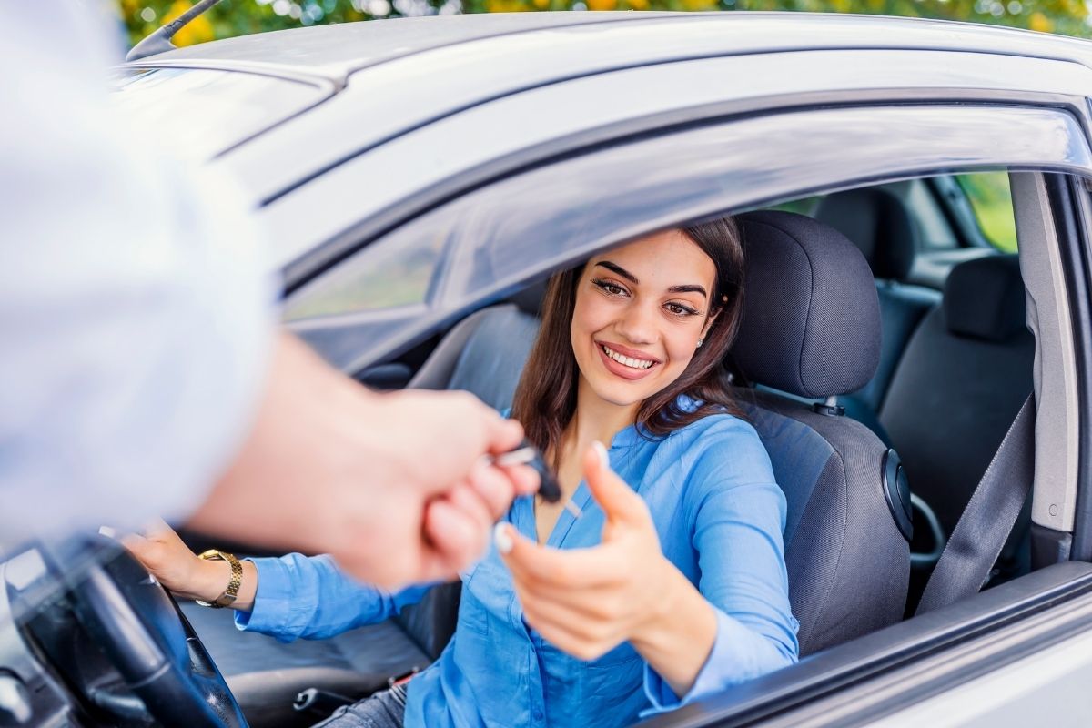 mulher recebendo as chaves de um carro alugado